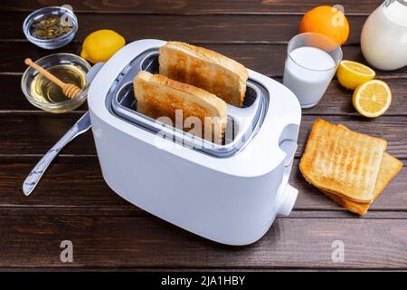 Dal tostapane fuoriescono fette di pane tostato. Cibi sani per la colazione e tecnologia di riscaldamento. Foto Stock