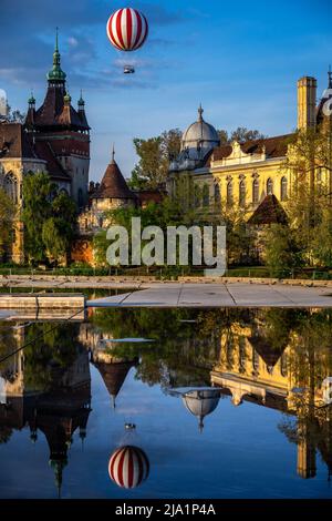 Mongolfiera che vola sopra il Castello di Vajdahunyad nel Parco cittadino di Budapest, con riflessi d'acqua Foto Stock