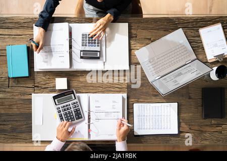 Angolo di Alta Vista di due imprenditori il calcolo di fatture in ufficio Foto Stock