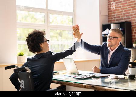 Imprenditore disabili dando alta cinque al suo sorridente Partner femminile in Office Foto Stock