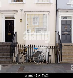 Londra, Greater London, Inghilterra, maggio 14 2022: Bicicletta fuori da pittoresche proprietà appena fuori dalla Kings Road nella zona di Chelsea. Foto Stock