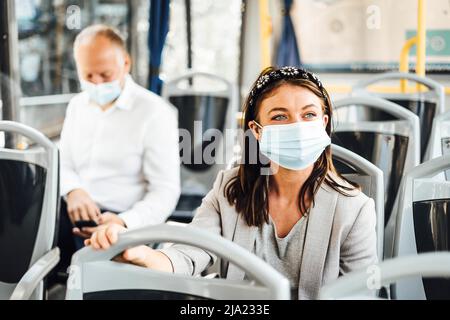 Viaggiatori che indossano maschere protettive che viaggiano con autobus pubblico Foto Stock