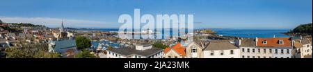 Vista panoramica sul porto di San Pietro e sul lungomare con Castle Cornet e l'isola di Herm sullo sfondo Foto Stock