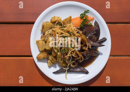 Fegato di maiale arrosto con cipolle fritte e patate fritte Foto Stock