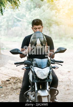 Uomo in moto che mette sul casco, motociclista che mette sul casco di sicurezza, persona in moto che mette sul casco di sicurezza Foto Stock