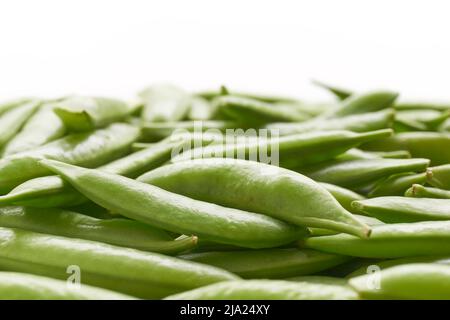 Primo piano di zucchero biologico fresco schiocco piselli o piselli a scatto su uno sfondo bianco. Sfondo vegetale con fuoco selettivo. Foto Stock