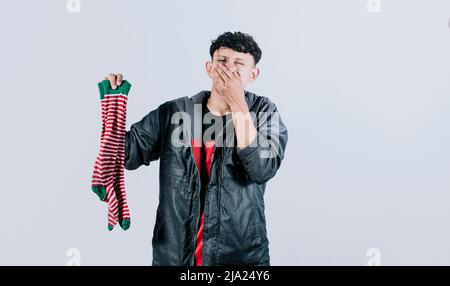 Persona che tiene un calzino stinky in mano, un uomo con un calzino in mano che copre il naso, puzzolente calzini concetto Foto Stock