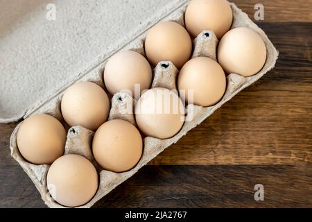 Vista dall'alto, dieci uova di pollo in un vassoio di cartone sul tavolo. Foto Stock