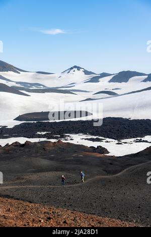 Due escursionisti sul sentiero attraverso la sabbia lavica, arido paesaggio vulcanico collinare di neve e campi di lava, sentiero escursionistico Fimmvoerouhals, Porsmoerk natura Foto Stock
