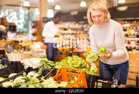 Donna acquistare verdure nel supermercato Foto Stock