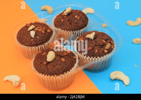 Muffin al cioccolato isolati su sfondo colorato. Delizioso muffin al cioccolato con noci. Foto Stock