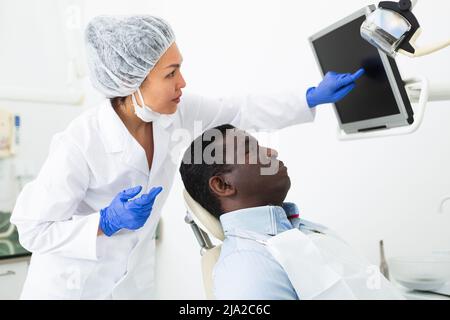 Dentista donna che indica il display per mostrare le informazioni al paziente Foto Stock