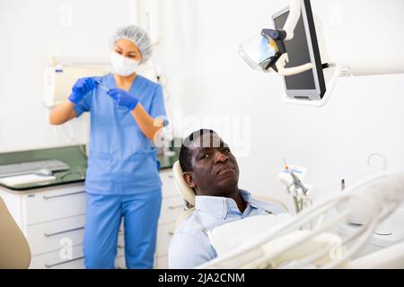 Paziente uomo pensivo seduto su sedia dentale e in attesa di esame Foto Stock