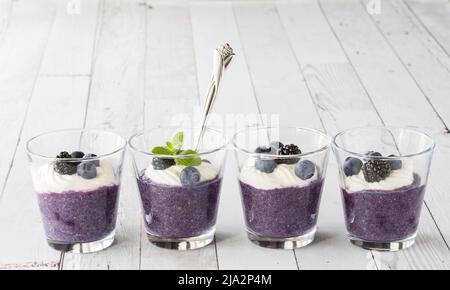 Una fila di parfait di budino chia al mirtillo con yogurt alla vaniglia e bacche. Foto Stock