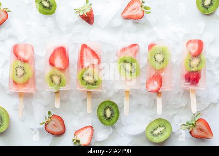 Fragole kiwi su ghiaccio circondate da fette di fragole e kiwi. Foto Stock