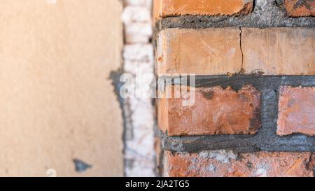 Muro di mattoni sullo sfondo della facciata smantellata e schiuma di plastica Foto Stock