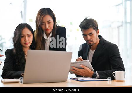 Un gruppo di imprenditori asiatici professionisti che hanno un incontro informale per brainstorm il loro progetto insieme in ufficio. Foto Stock