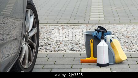 prodotti per la pulizia dell'auto e un'auto sporca fianco a fianco Foto Stock