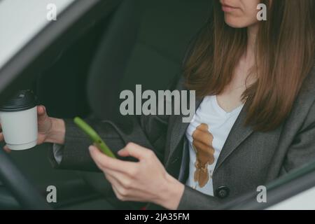 La donna ha versato il caffè caldo su se stessa mentre si testava durante la guida. Vita quotidiana macchia sporca Foto Stock
