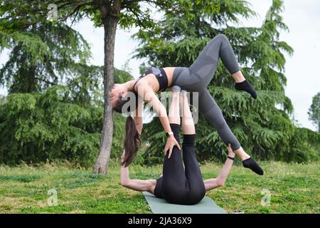 Giovane coppia sportiva che pratica acro-yoga in un parco. Foto Stock