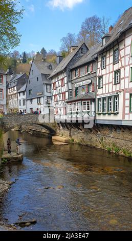 Tradizionali case tedesche a graticcio lungo il fiume Ruhr nella storica città di Monschau, in Germania. La gente pesca nel fiume. Foto Stock