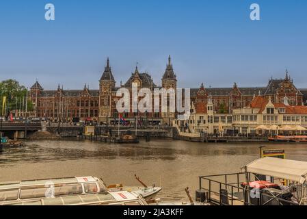 Amsterdam, Paesi Bassi, maggio 2022. La stazione centrale di Amsterdam e le barche da crociera sul canale presso il Damrak di Amsterdam. Foto di alta qualità Foto Stock