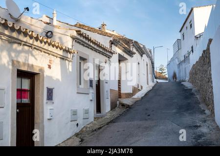 Architettura tipica degli edifici della regione dell'Algarve con strade strette, strade acciottolate decorate con fiori, vasi, colori e camini. Foto Stock