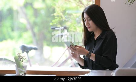 Giovane donna manager che ha una conversazione di lavoro tramite smartphone mentre si siede in un bar. Foto Stock