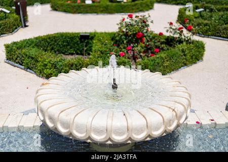 Fontana. Fontana di pietra piena di acqua con un'esplosione di primavera con fiori colorati in tutto il parco di Madrid in una giornata limpida Foto Stock