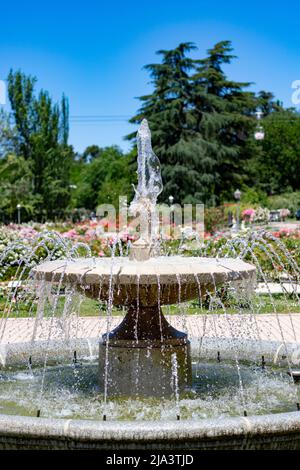 Fontana. Fontana di pietra piena di acqua con un'esplosione di primavera con fiori colorati in tutto il parco di Madrid in una giornata limpida Foto Stock