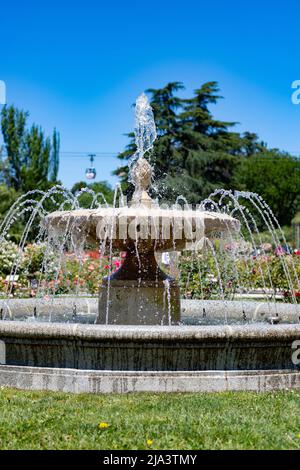 Fontana. Fontana di pietra piena di acqua con un'esplosione di primavera con fiori colorati in tutto il parco di Madrid in una giornata limpida Foto Stock