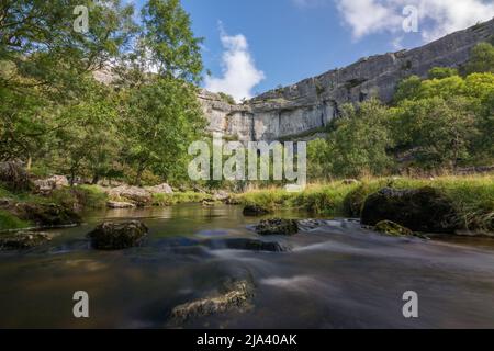 Una lunga esposizione dal centro del torrente Malham Cove, guardando verso le imponenti scogliere calcaree della famosa Cove. Yorkshire Dales. Foto Stock