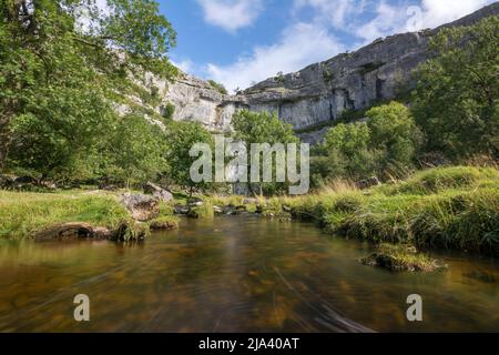 Una lunga esposizione dal centro del torrente Malham Cove, guardando verso le imponenti scogliere calcaree della famosa Cove. Yorkshire Dales. Foto Stock