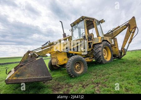 Un vecchio caricatore retroescavatore Ford si trova al sole di un campo vicino ad Appleby, Yorkshire. Avvistato mentre si fa la passeggiata Dales High Way. Foto Stock