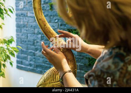 Una donna designer ripristina e copre una statuetta in legno fenicottero con lamina d'oro. Il processo di doratura manuale Foto Stock