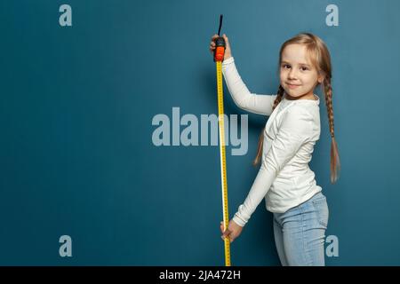 Cute bambino sta giocando. Il bambino misura su sfondo blu ritratto. Concetto di istruzione. Foto Stock