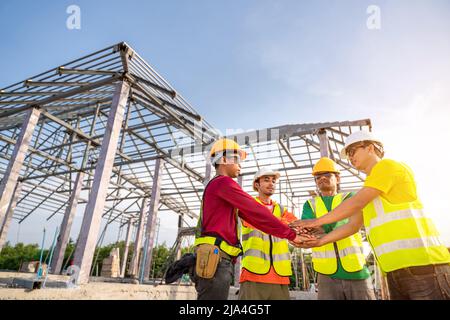 Gli architetti e ingegneri edili si uniscono alle mani mentre lavorano in cantieri all'aperto. Concetto di collaborazione per la costruzione di edifici. Teamw Foto Stock