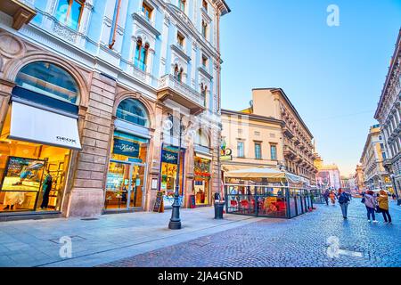 MILANO, ITALIA - 5 APRILE 2022: Piacevole passeggiata serale lungo Via Dante, passando attraverso le numerose e luminose finestre dei negozi, delle boutique e dei ristoranti all'aperto, Foto Stock