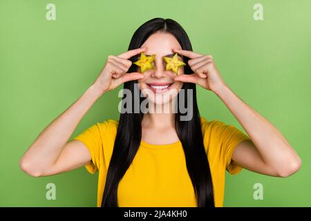 Foto di bambina foling donna indossare giallo t-shirt tenuta frutta tropicale coperchio occhi isolato verde sfondo di colore Foto Stock