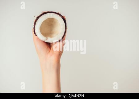 olio di cocco e di cocco in una mano su un isolato bianco Foto Stock