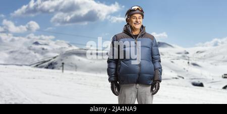 Uomo maturo in giacca invernale in piedi in una stazione sciistica su una montagna innevata Foto Stock