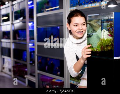 Ragazza che guarda i pesci giovani in acquario Foto Stock