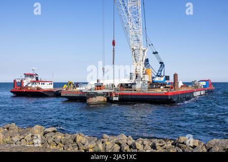 Lelystad, Paesi Bassi - 22 aprile 2022: Nave gru e nave di rifornimento occupato con demolizione vecchia turbina eolica offshore Foto Stock