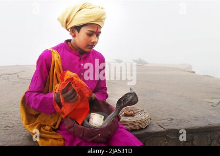 India, Utttar Pradesh, Benares (Varanasi) Ritratto di un giovane incantatore di serpenti sui ghats della città Foto Stock