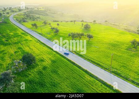 Paesaggio verde campagna con un'auto che percorre una strada asfaltata e un'auto, vista con droni dall'alto Foto Stock