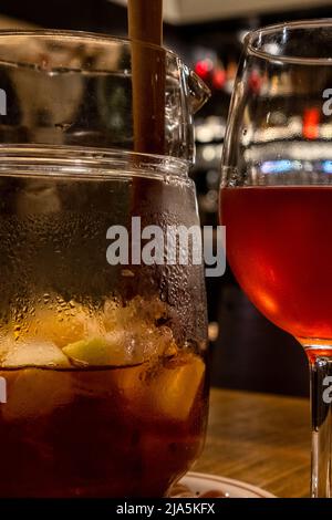 Una caraffa di sangria accompagnata da due bicchieri allineati su un tavolo di legno. Foto Stock