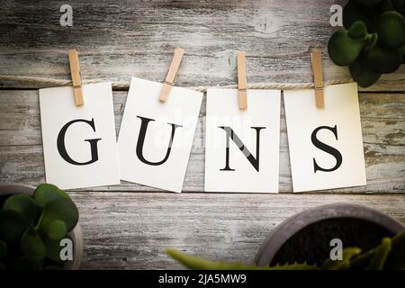 Un insieme di schede stampate che ortografia le PISTOLE di parola su un vecchio sfondo di legno. Foto Stock