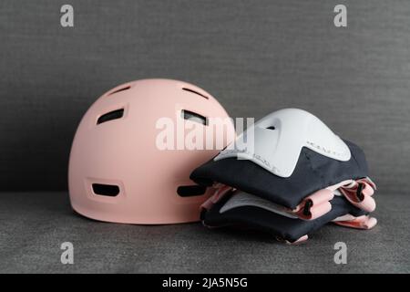 Casco rosa su sfondo grigio scuro. Protezione di sicurezza per attività esterne dei bambini Foto Stock