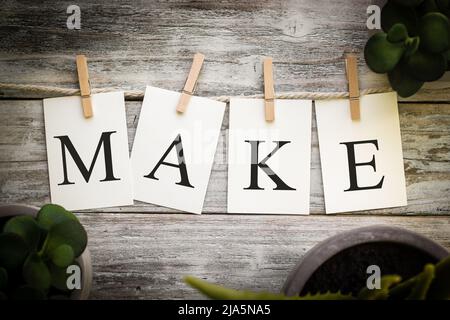 Un insieme di schede stampate che ortografia la parola FARE su uno sfondo di legno invecchiato. Foto Stock