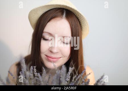 portait di una bella giovane donna con cappello estivo e fiori di lavanda Foto Stock